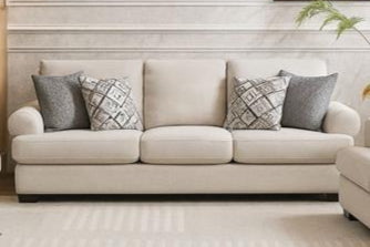 Modern living room with beige sofa set and decorative elements.